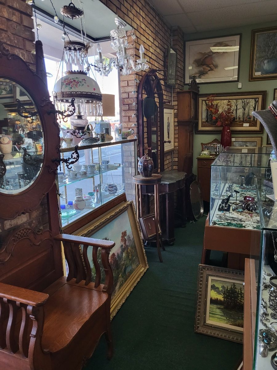Antique shop interior with furniture, paintings, and glass display cases.