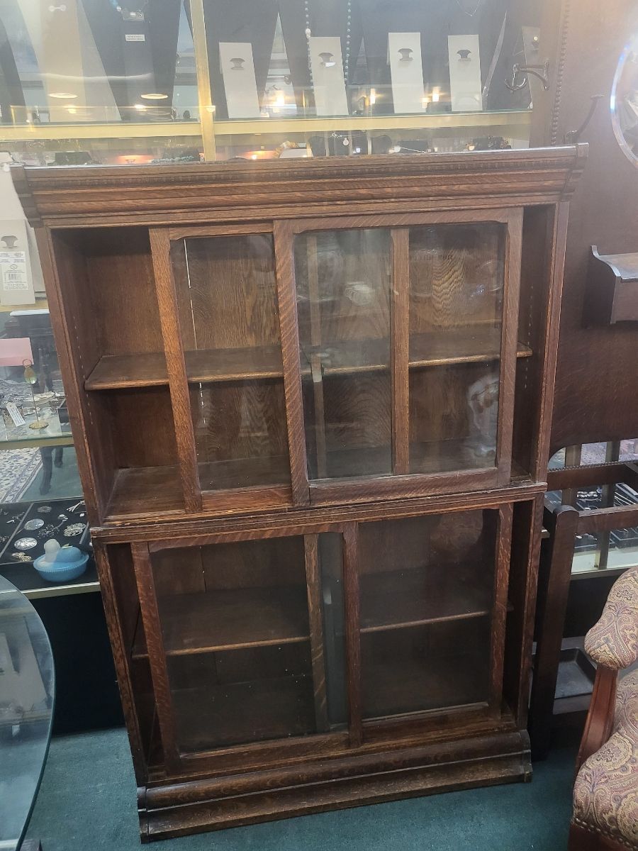 Wooden antique bookcase with glass doors, inside a shop setting.