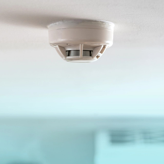 Rilevatore di fumo bianco montato sul soffitto sopra un interno della stanza sfocato