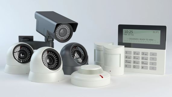 Kit di sistema di sicurezza con quattro telecamere, sensore di movimento e pannello di controllo con tastiera su sfondo bianco.