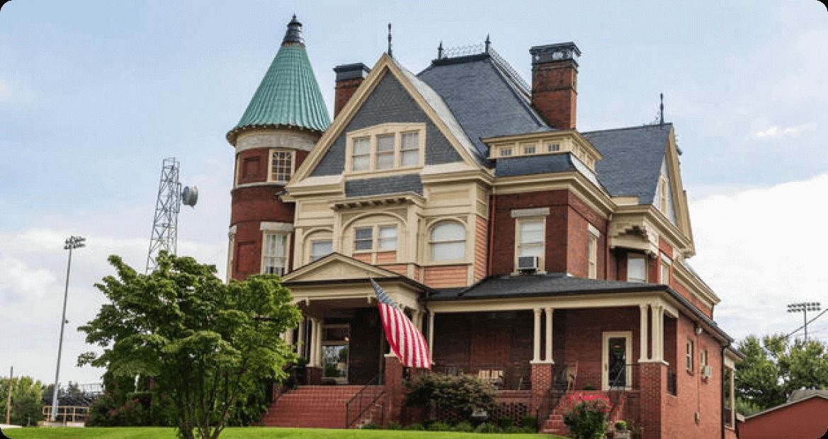 Victorian house with a turret, ornate trim, and a front porch with an American flag