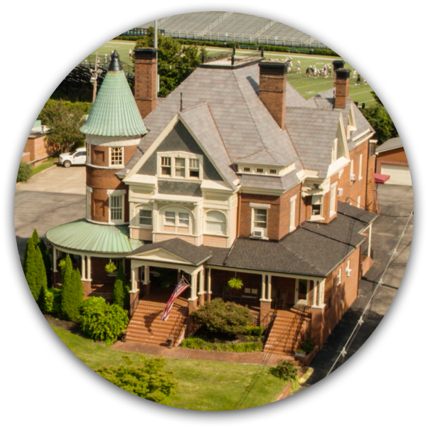 Miniature Victorian-style house model with gray roof, green turret, and brown brick details
