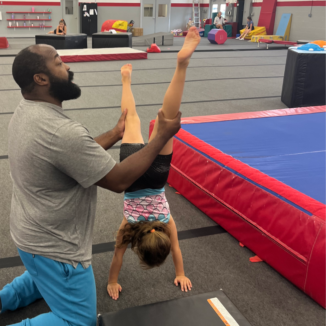 young girl gymnast assisted by coach