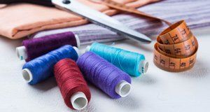 Spools of thread , scissors , and a measuring tape on a table.