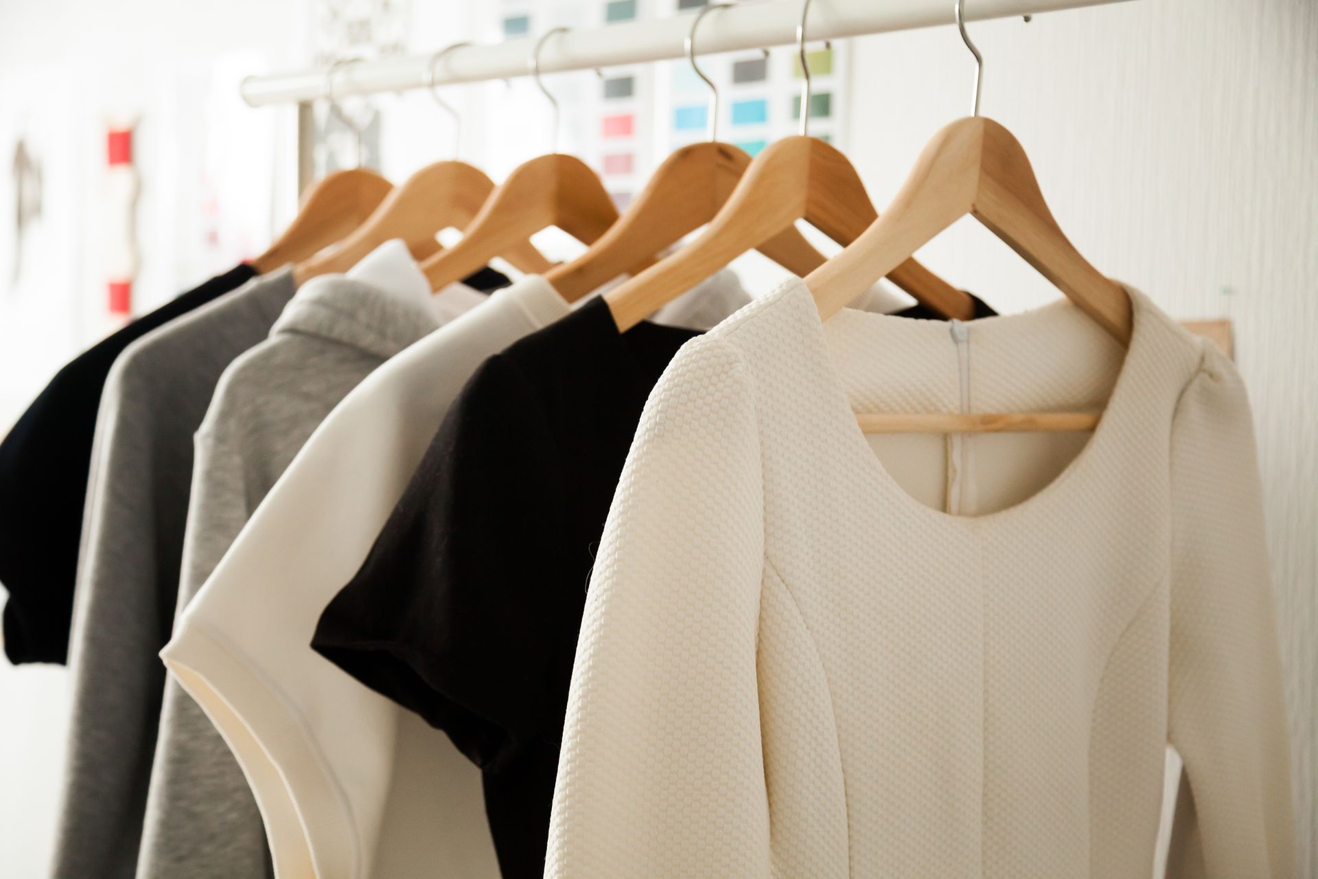 A row of clothes hanging on wooden hangers in a closet.
