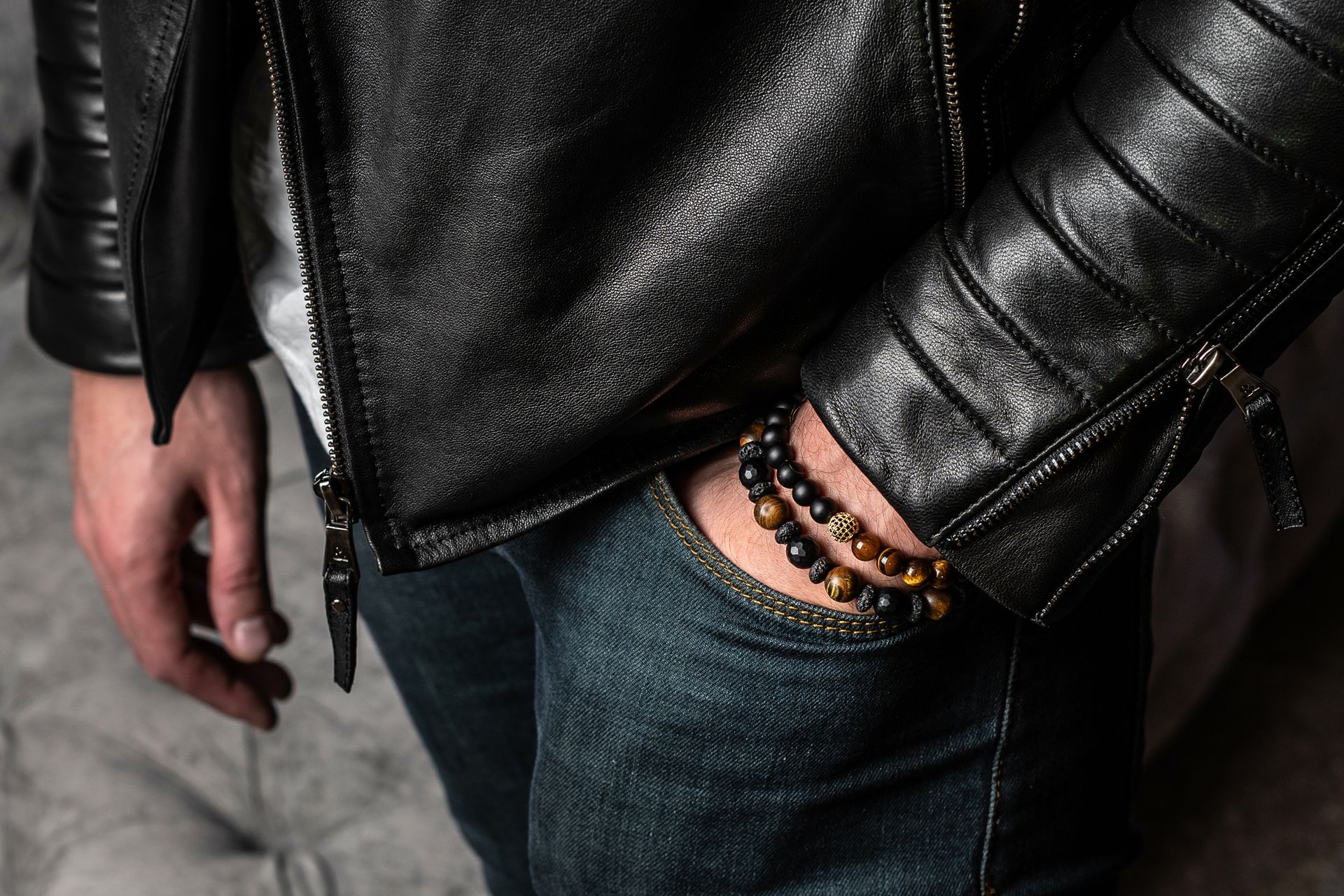 A man wearing a leather jacket and a bracelet on his wrist.