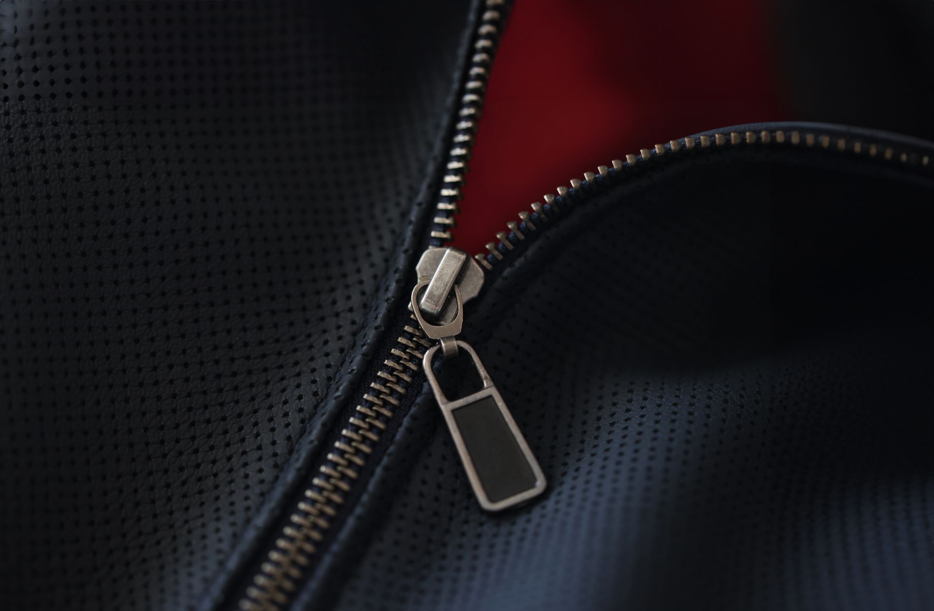 A close up of a zipper on a black leather jacket