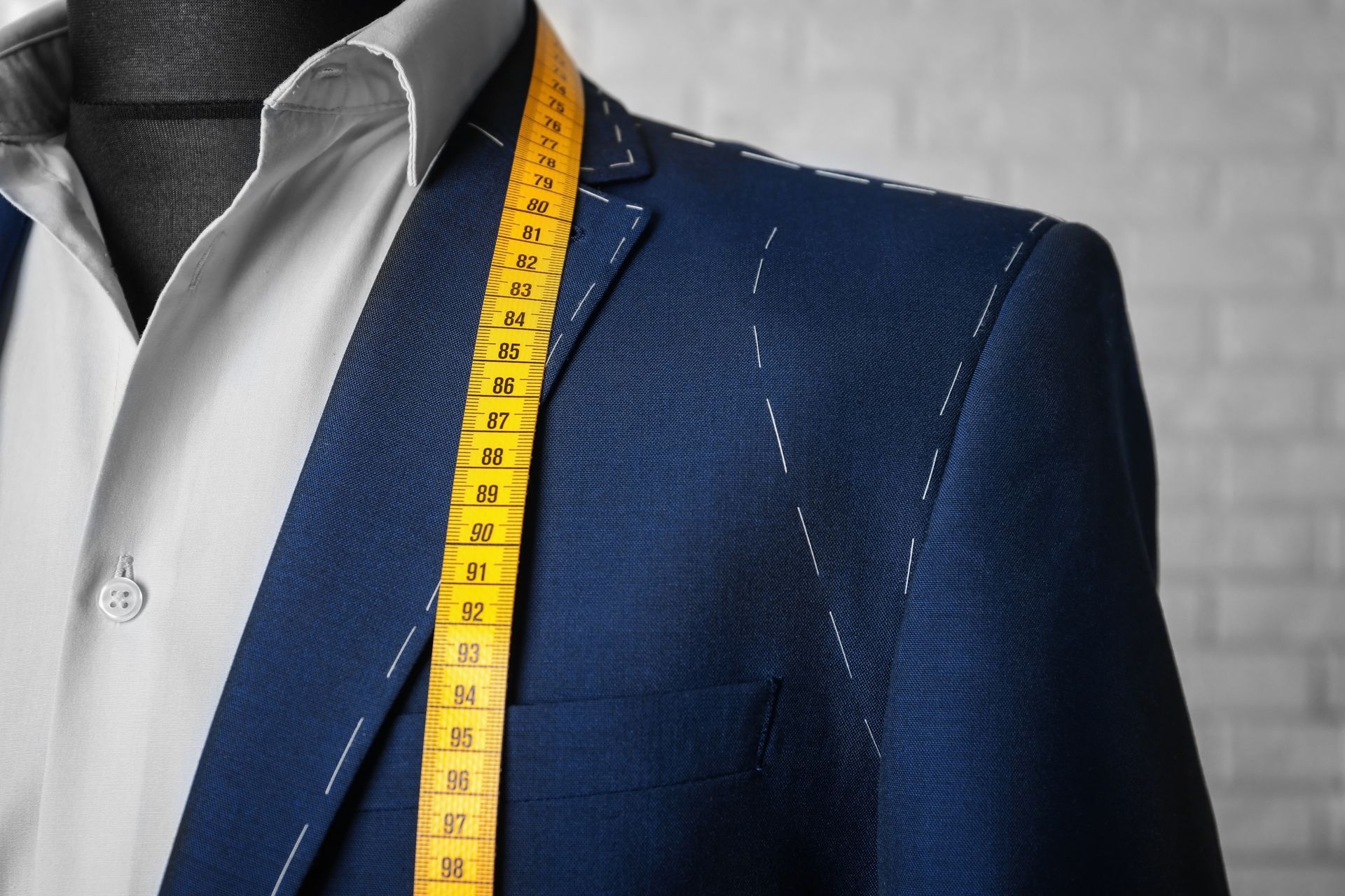 A man in a suit is being measured by a tape measure.
