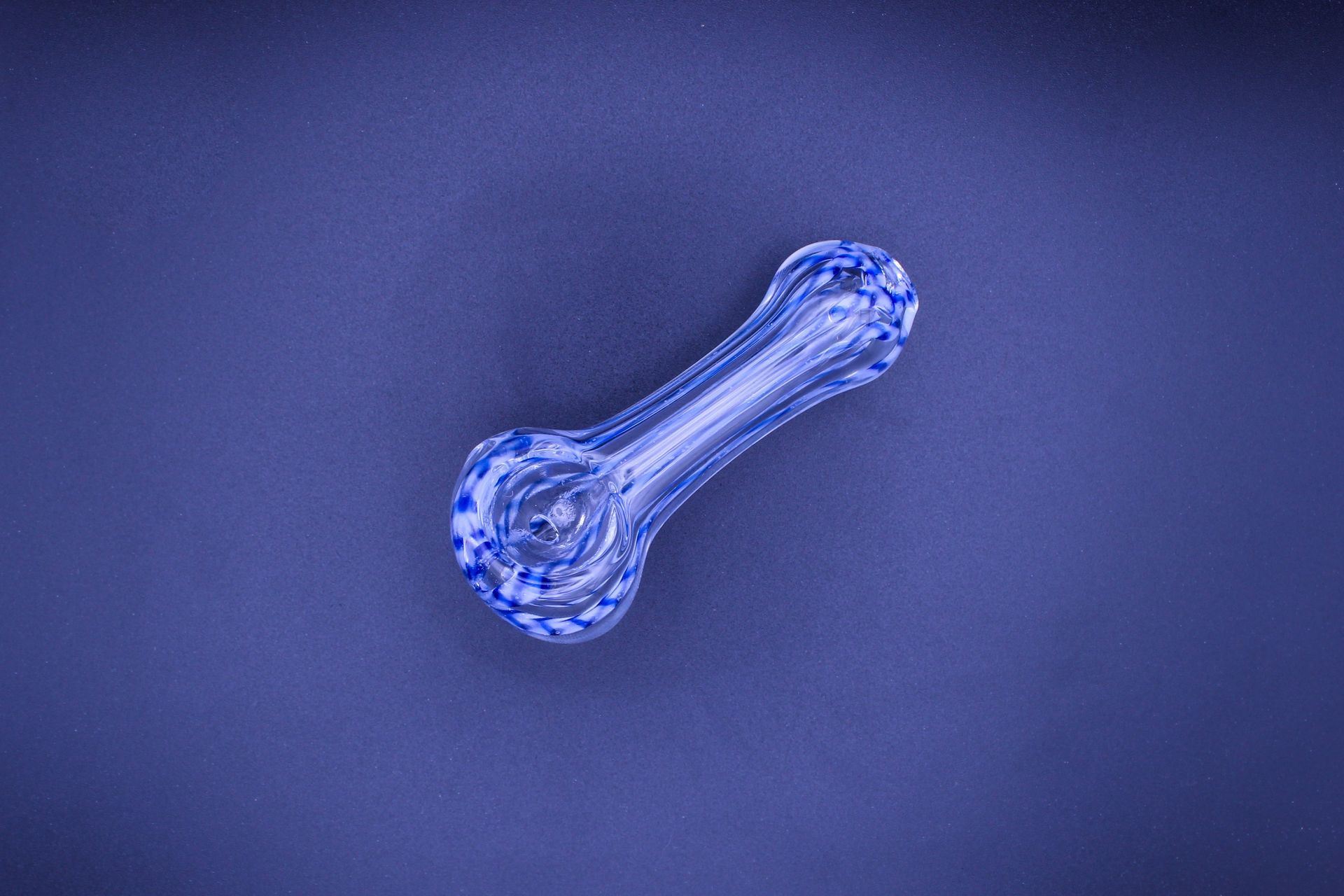 A blue glass pipe is sitting on a blue surface.