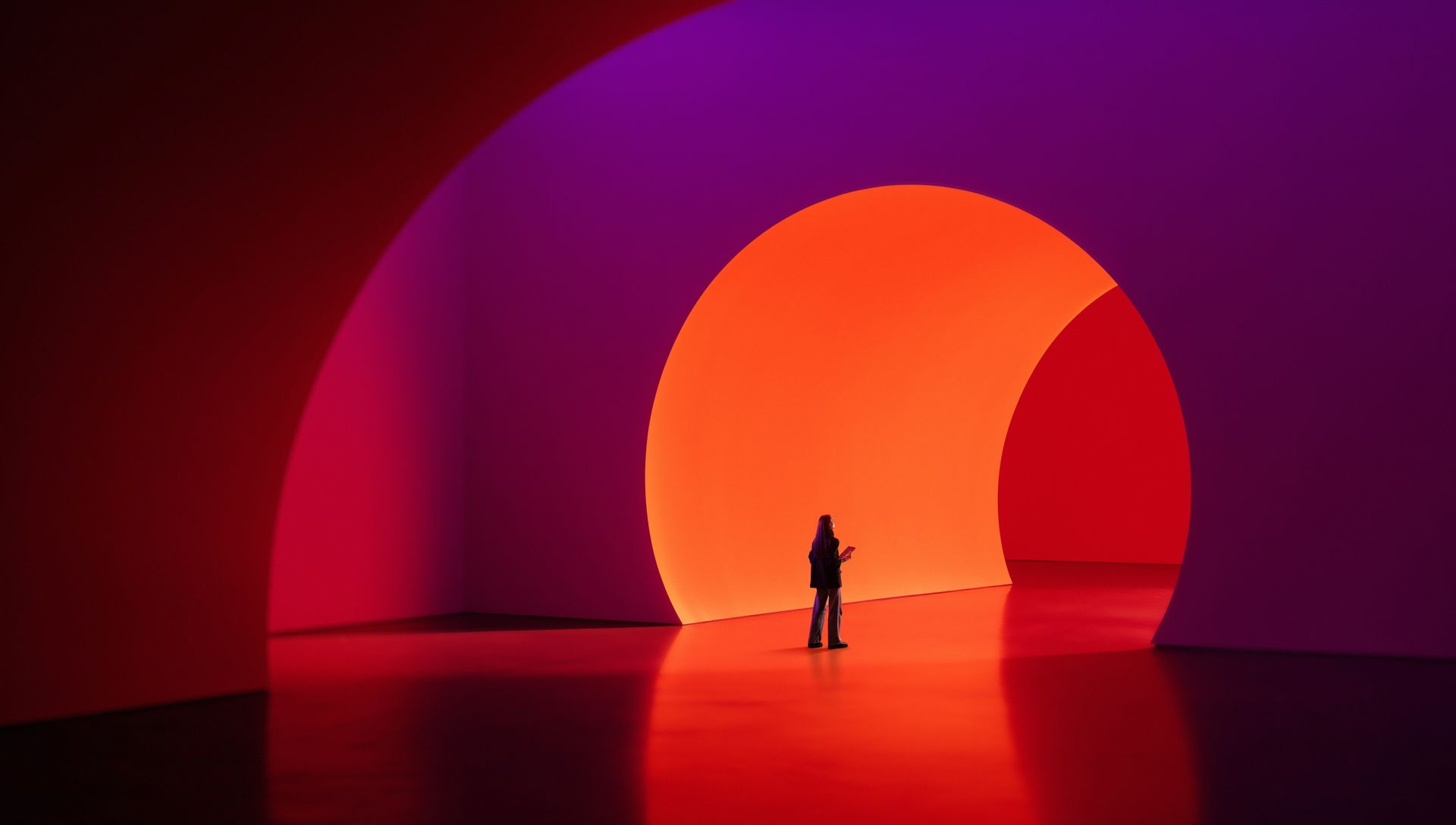Silhouetted person under glowing orange arches in a red-lit modern space