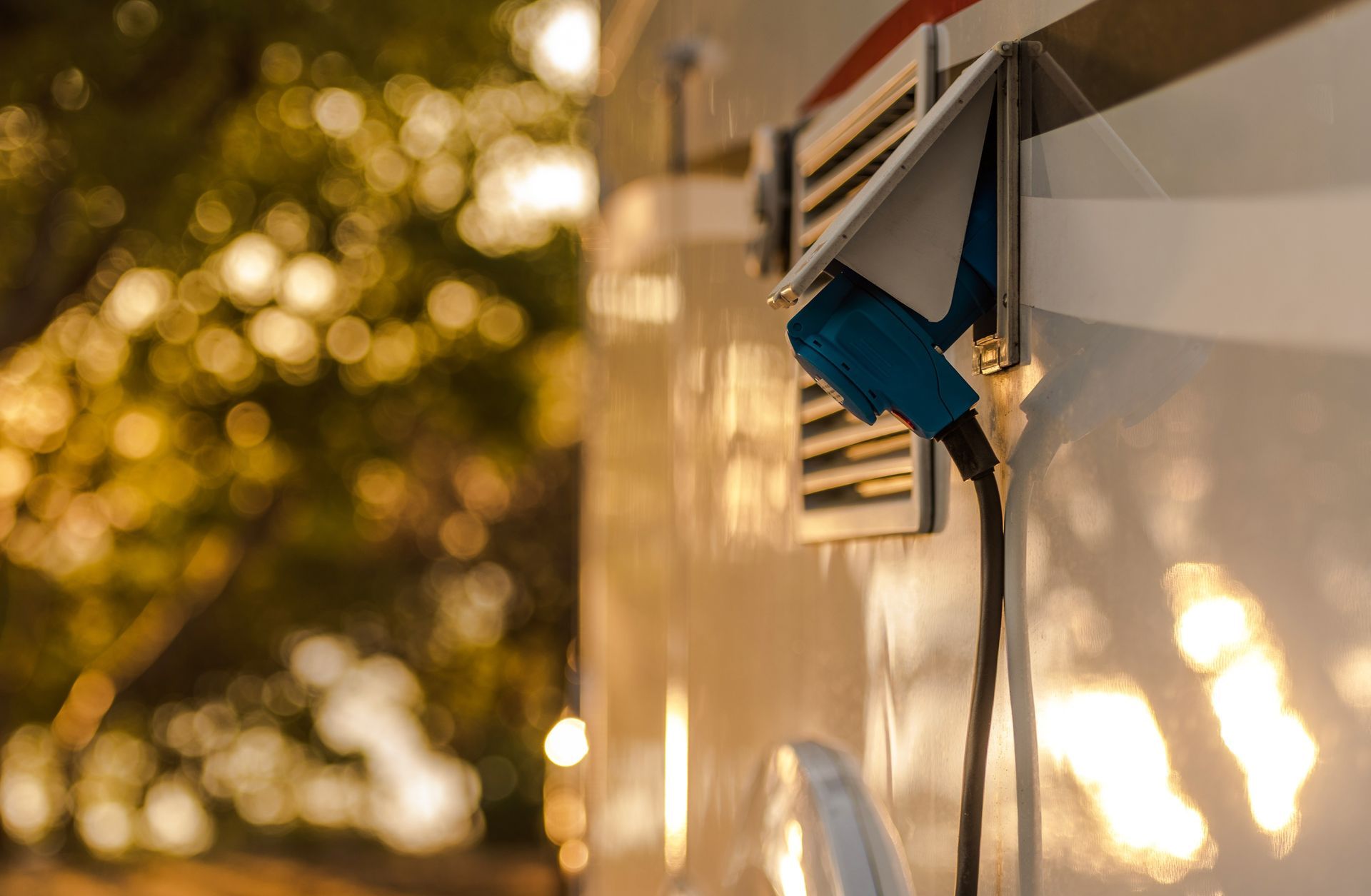 Close-up of a blue camper vent on a white RV in warm sunset light.