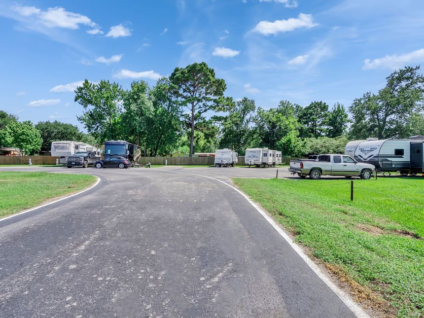 Emergency vehicles and a camper van parked on grass beside a gravel road