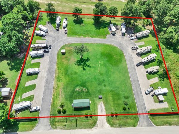 Aerial view of an RV park with white trailers around a grassy central area, outlined in red.