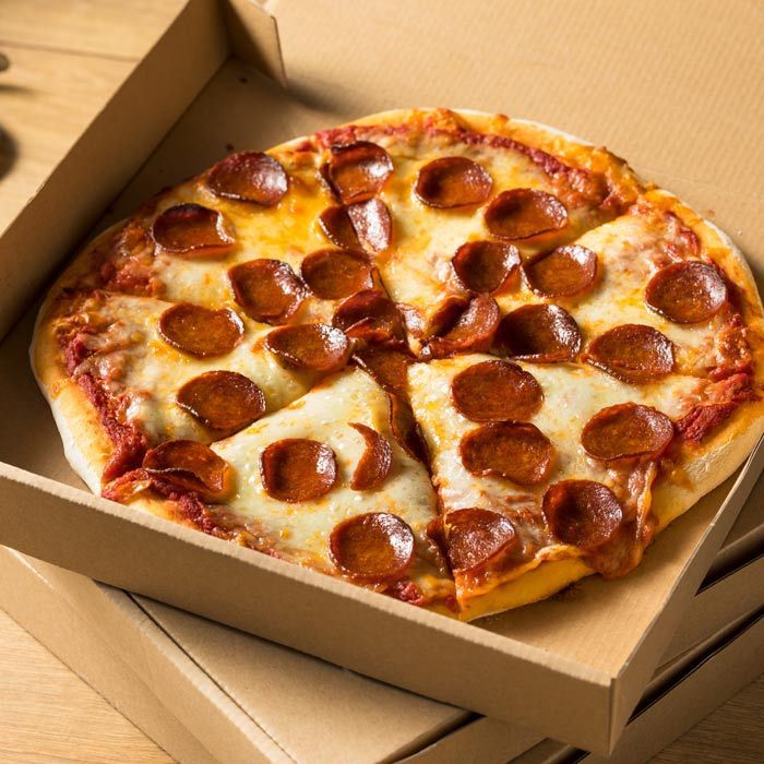 Pepperoni pizza in an open cardboard box on a wooden table