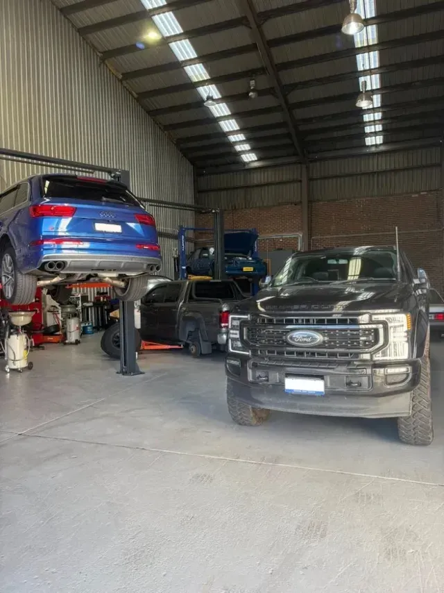 A Garage Interior with A Black Ford Pickup and A Blue SUV on A Lift — Level Up Automotive In Unanderra, NSW