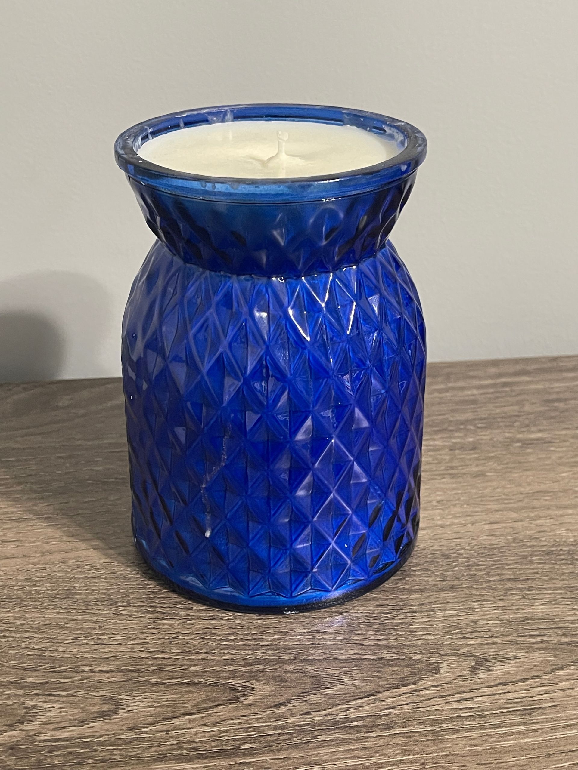 Blue textured glass candle on a wooden surface.