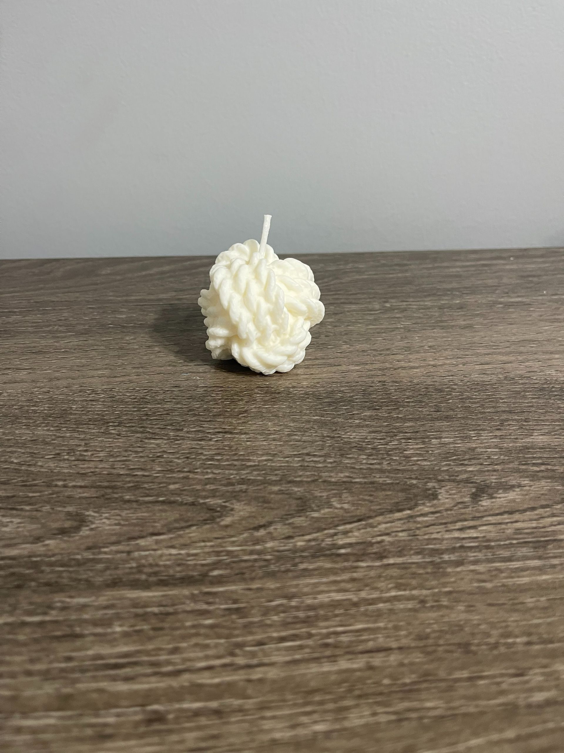 Cream-colored knot candle on a wooden surface.