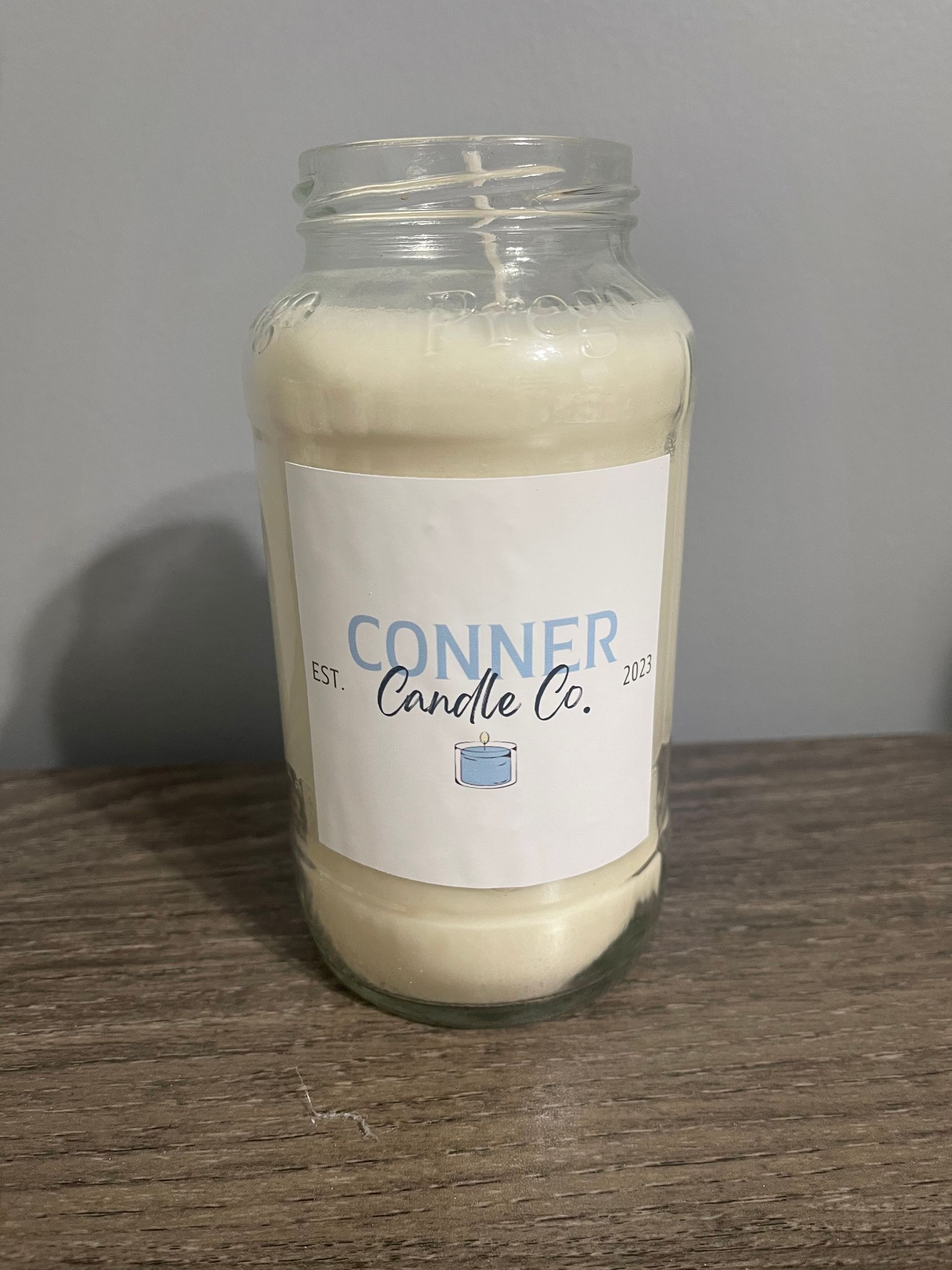 White candle in a jar with a label that says "CONNER Candle Co.".