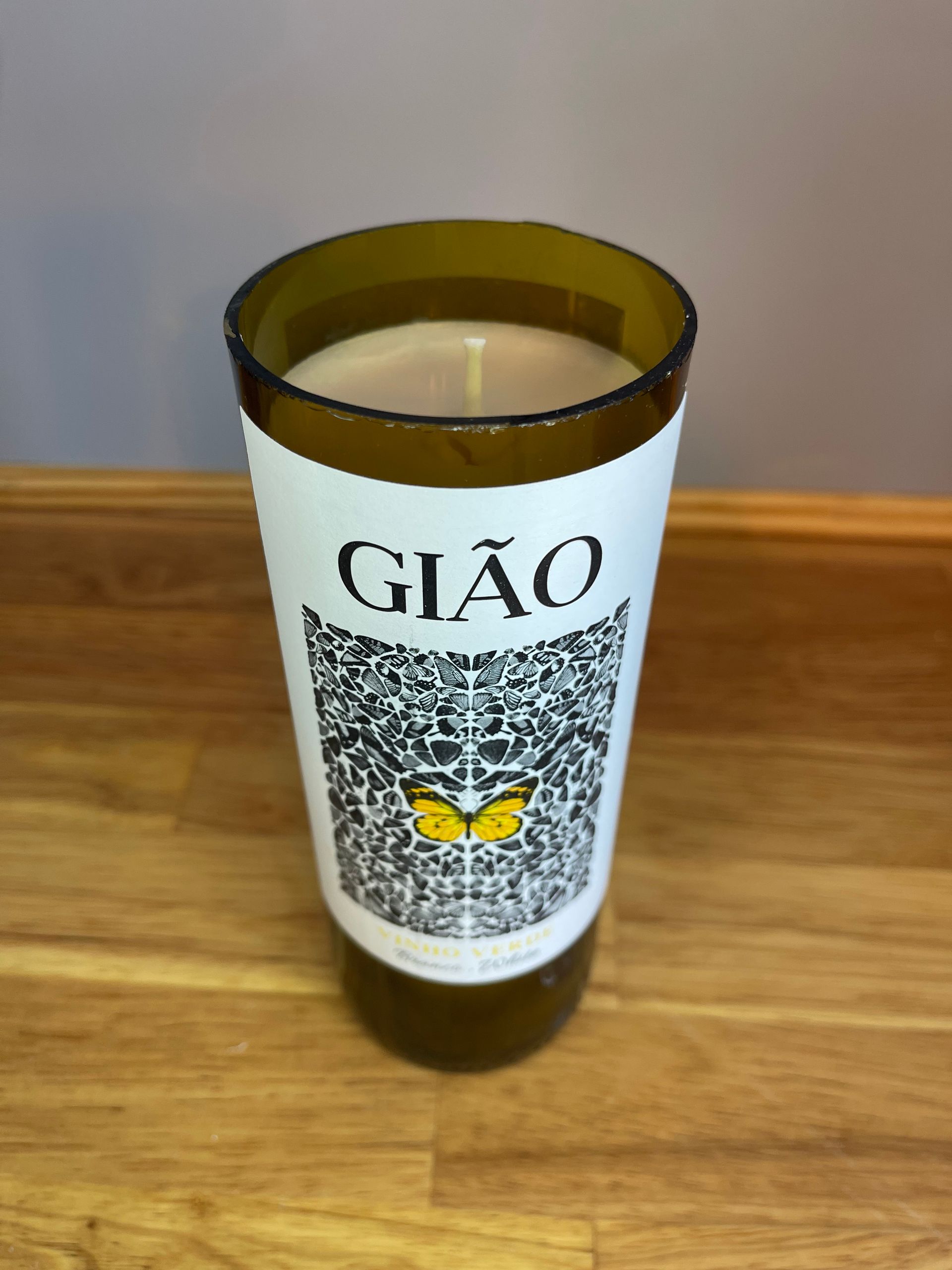 Gold bottle with white label reading “GIÃO” on a wooden surface.