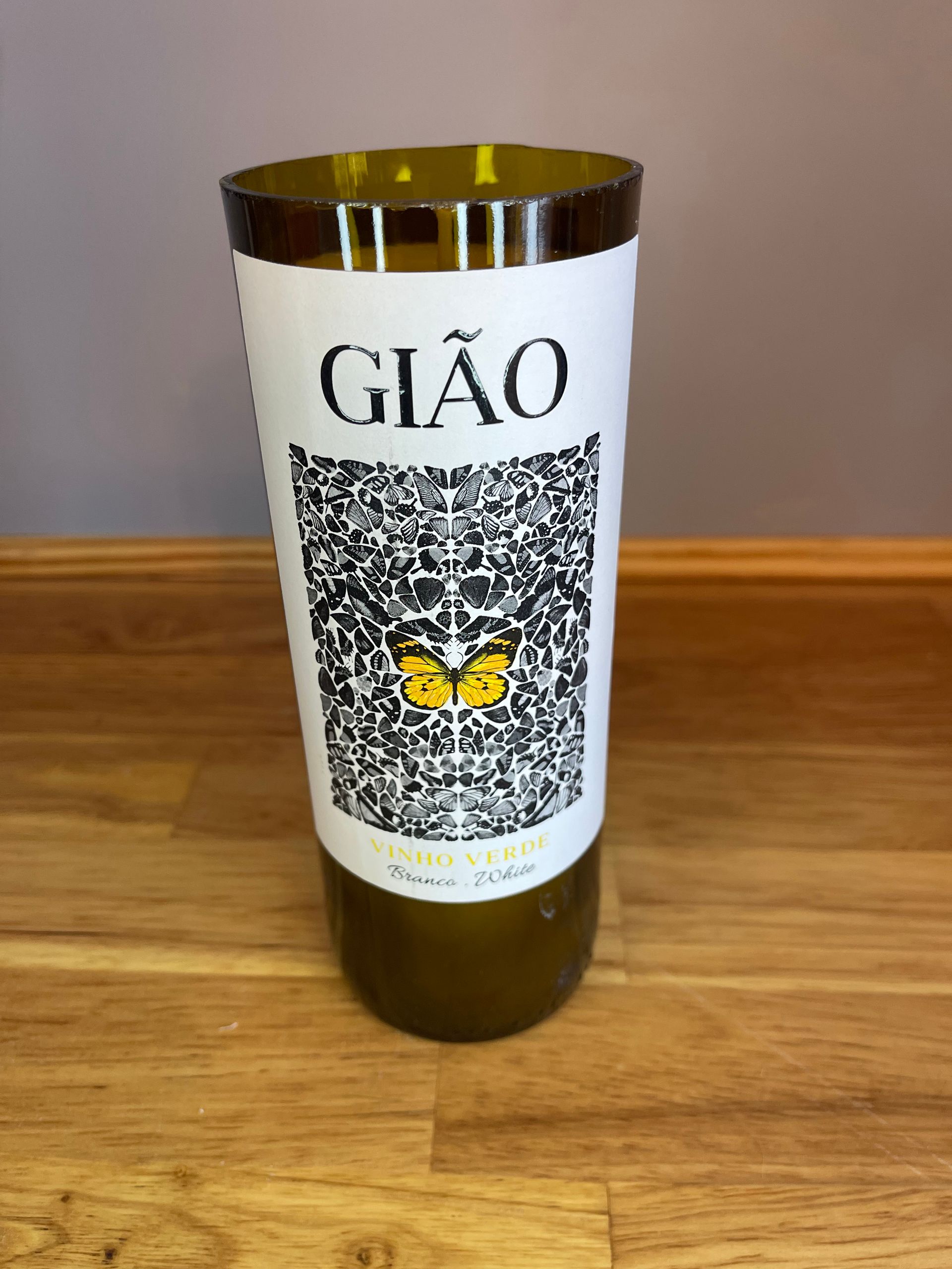 Gold bottle with white label reading “GIÃO” on a wooden surface.