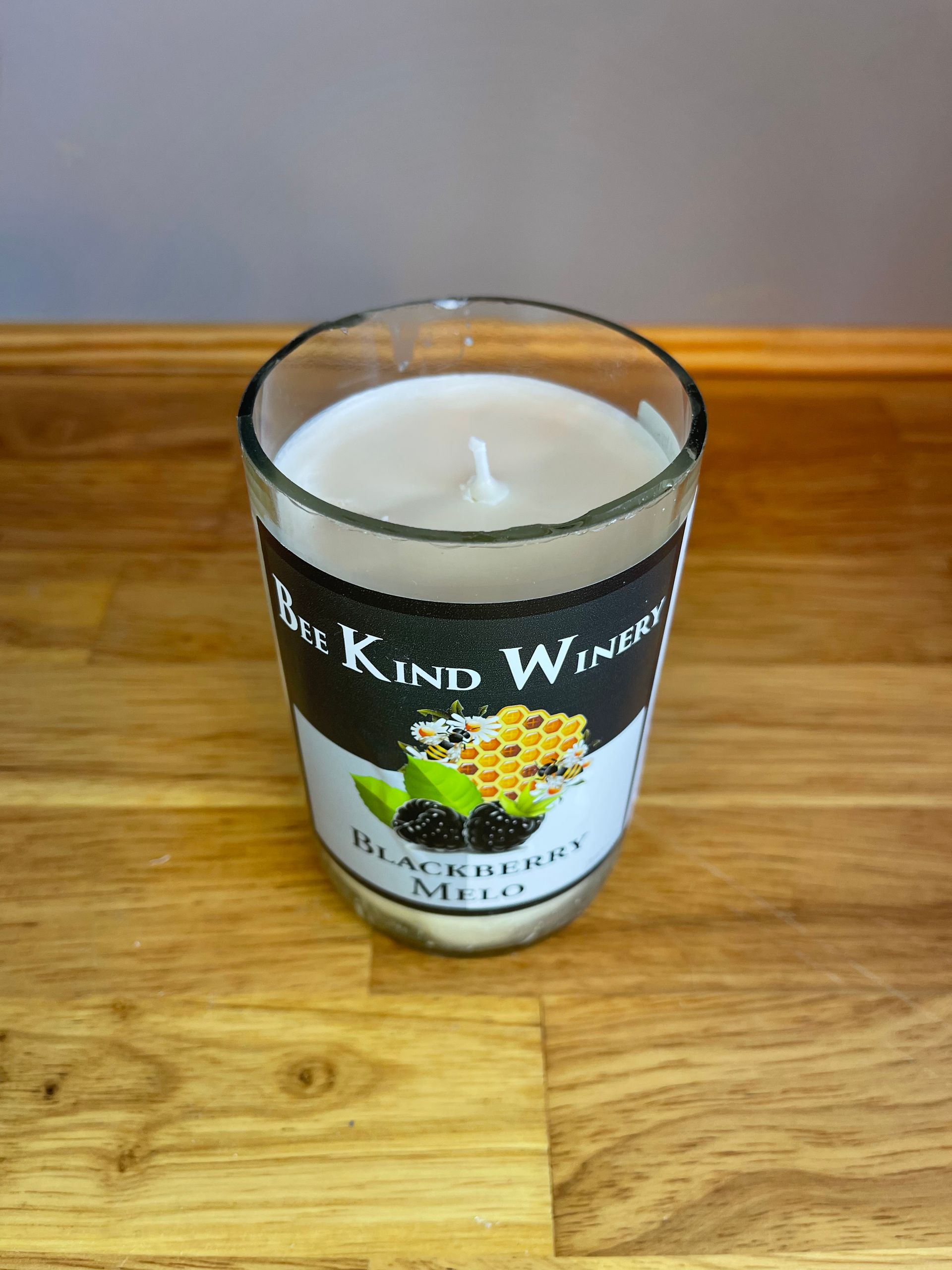 Blackcurrant wine glass candle on a wooden table against a gray wall