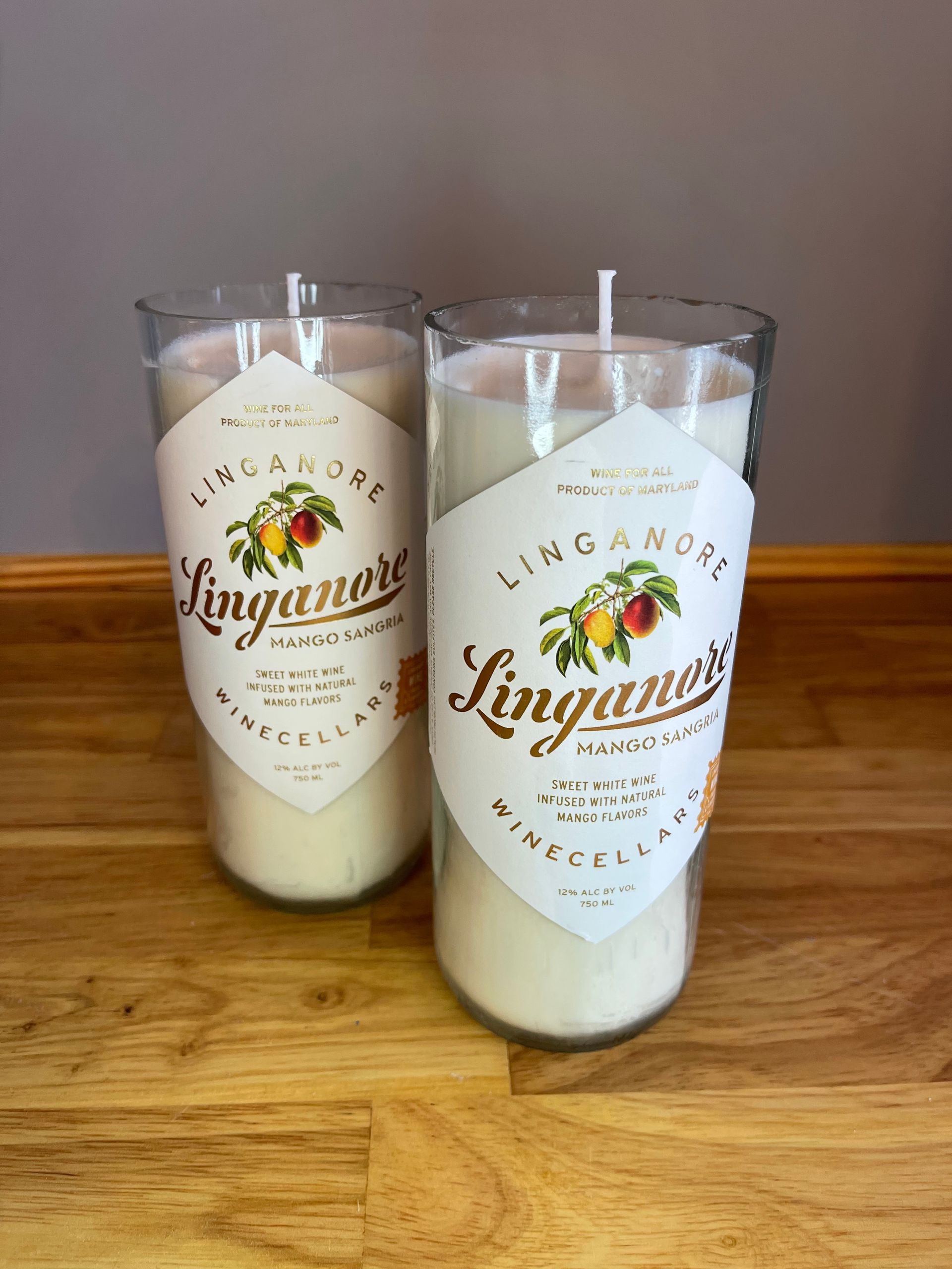 Two clear tumblers with white candles and gold “Linganore” labels on a wooden table