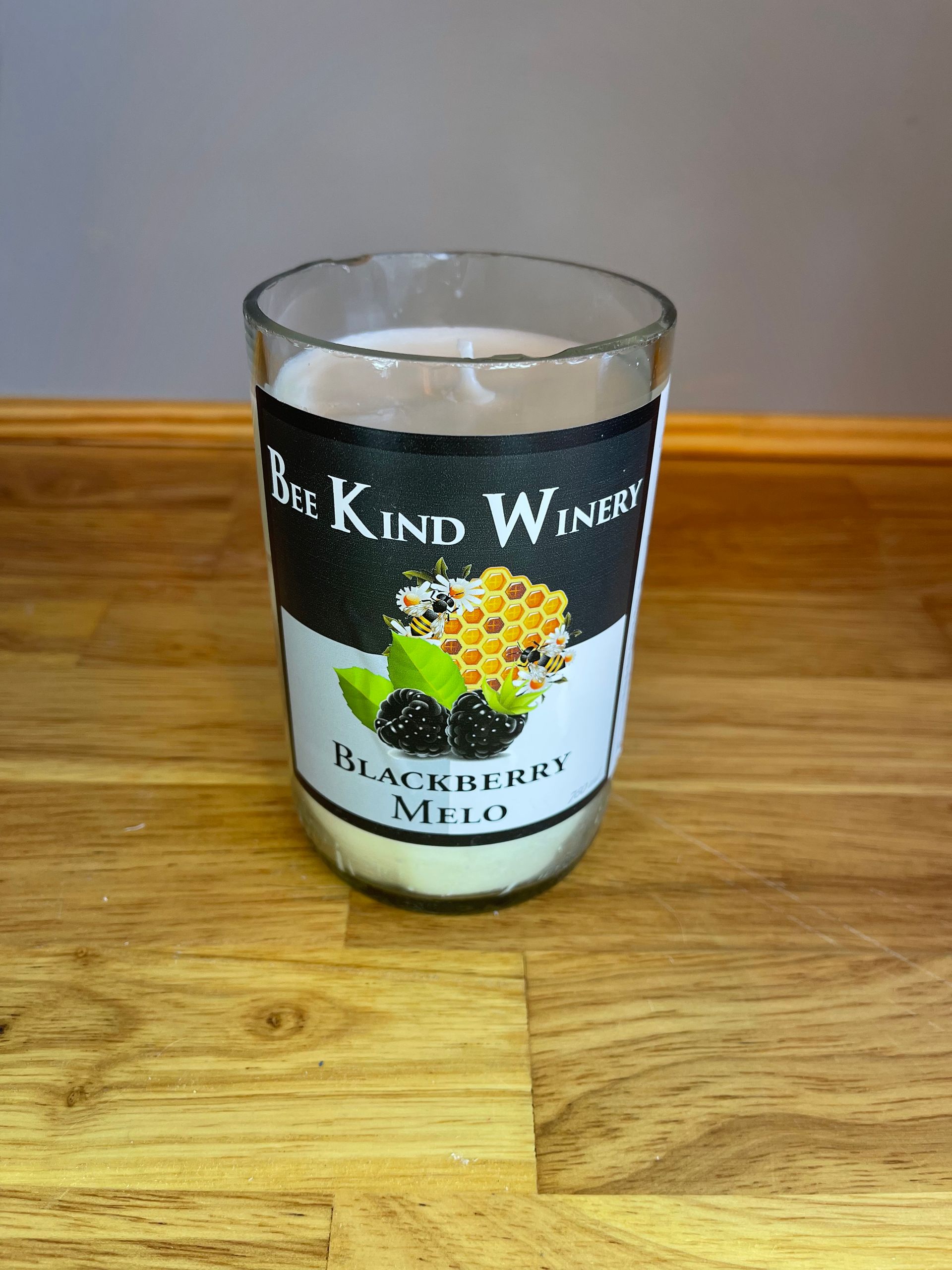 Blackcurrant wine glass candle on a wooden table against a gray wall