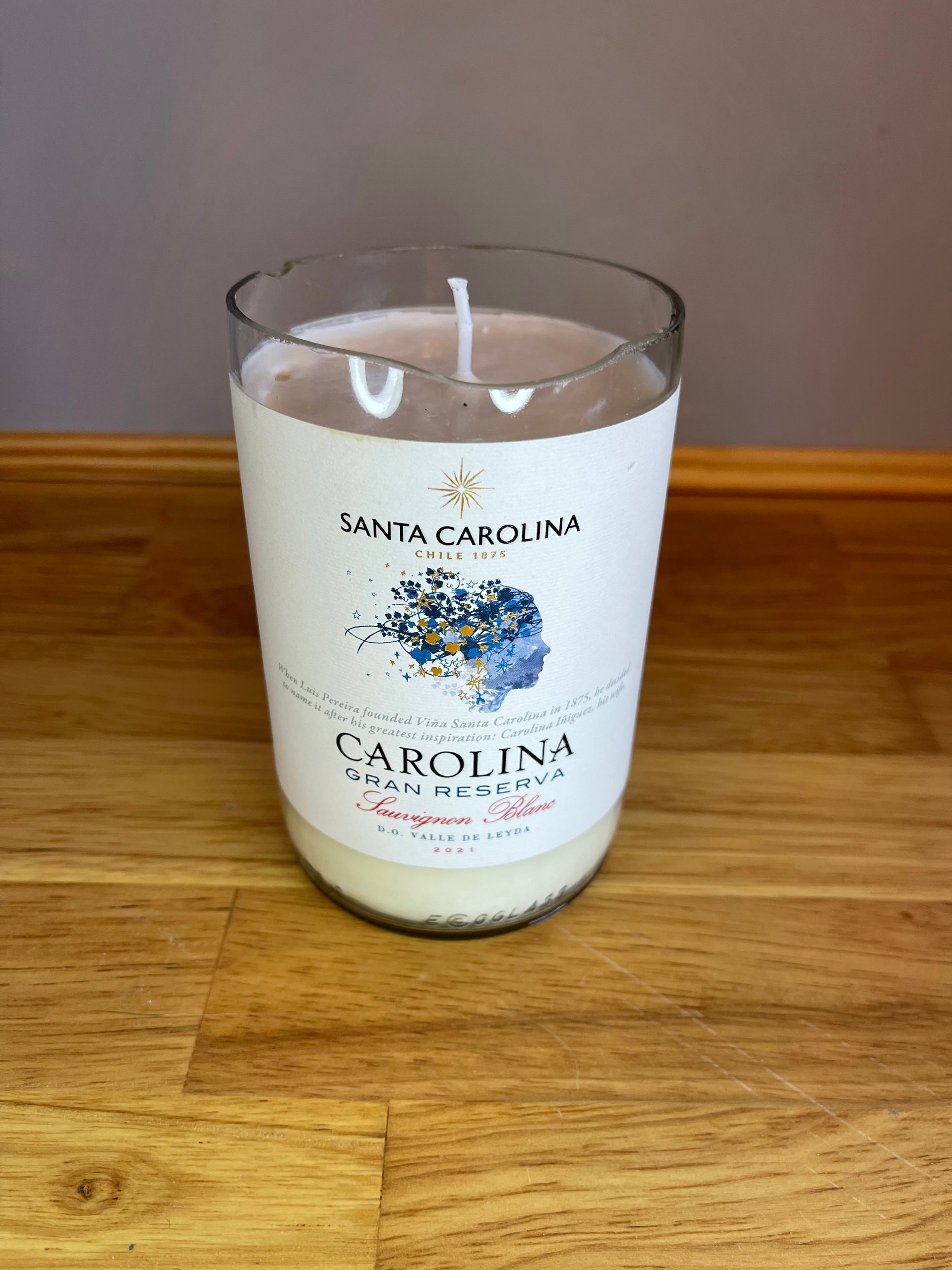 White Carolina Inn candle jar on a wooden table against a wood floor background