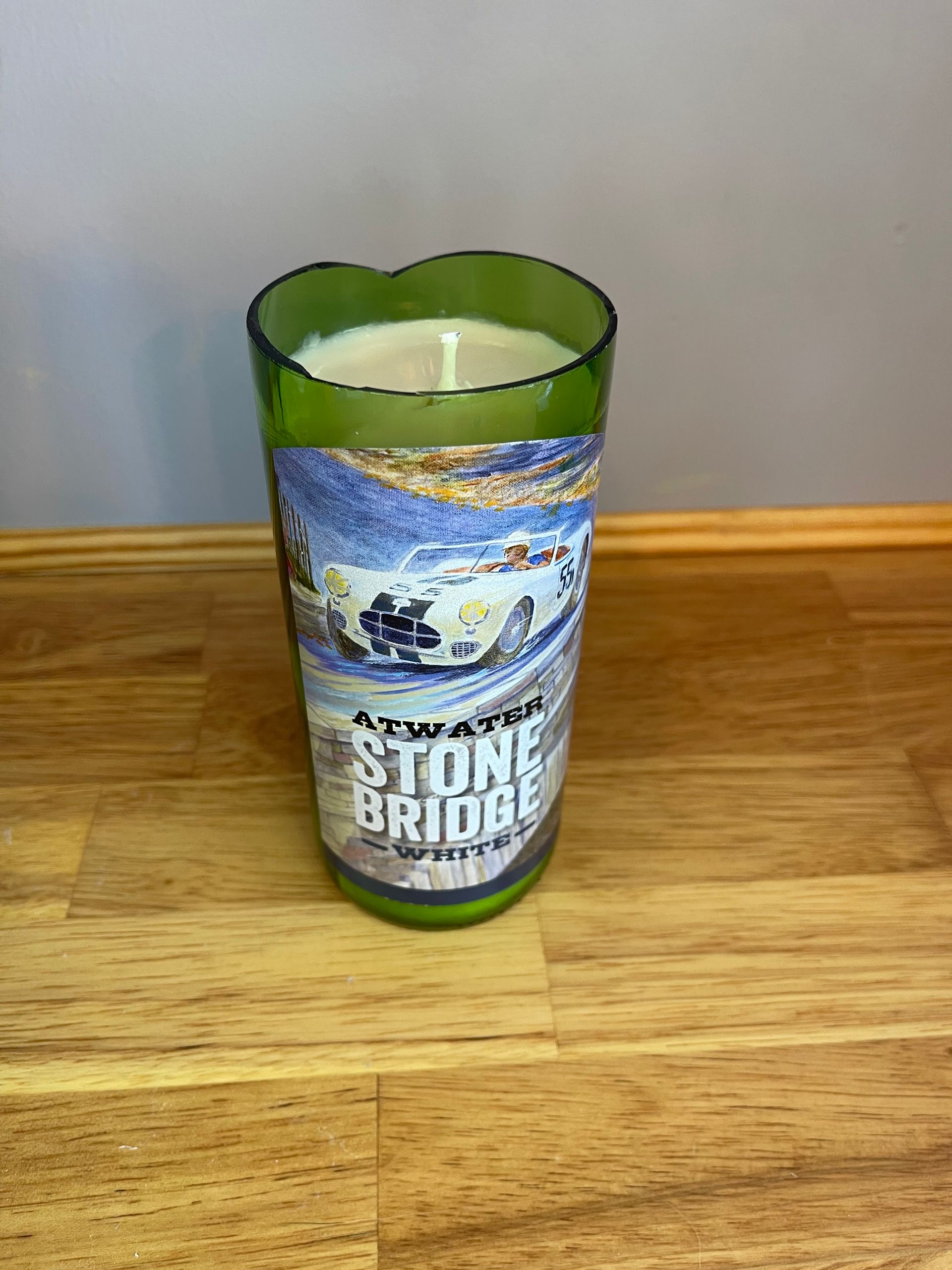 Green glass candle holder labeled “Stone Bridge” on a wooden table.