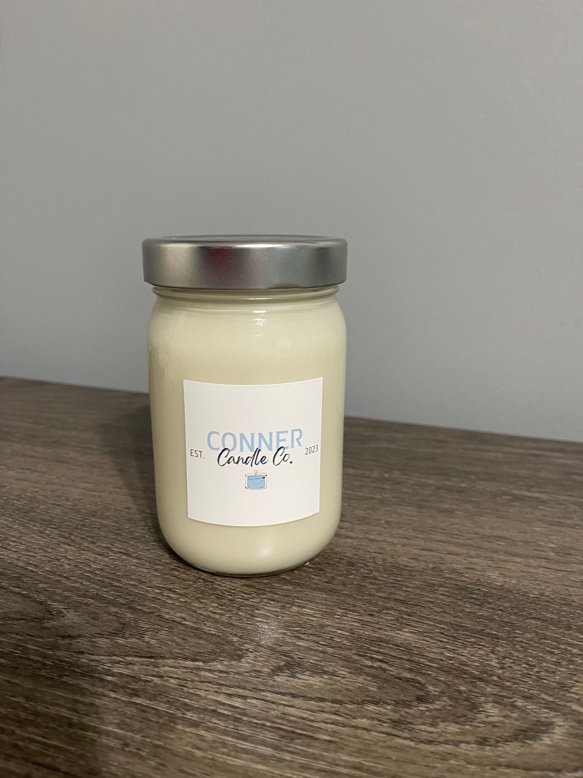 Mason jar candle with silver lid and a white label that says "Conner Candle Co."