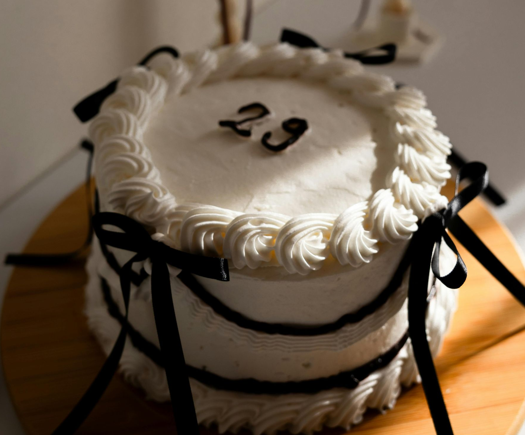 White frosted cake with black ribbon and number 39 on top, on a wooden table