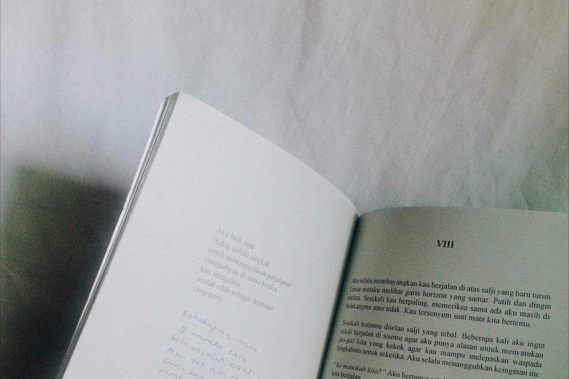 Open book on a textured white surface, pages displaying text.