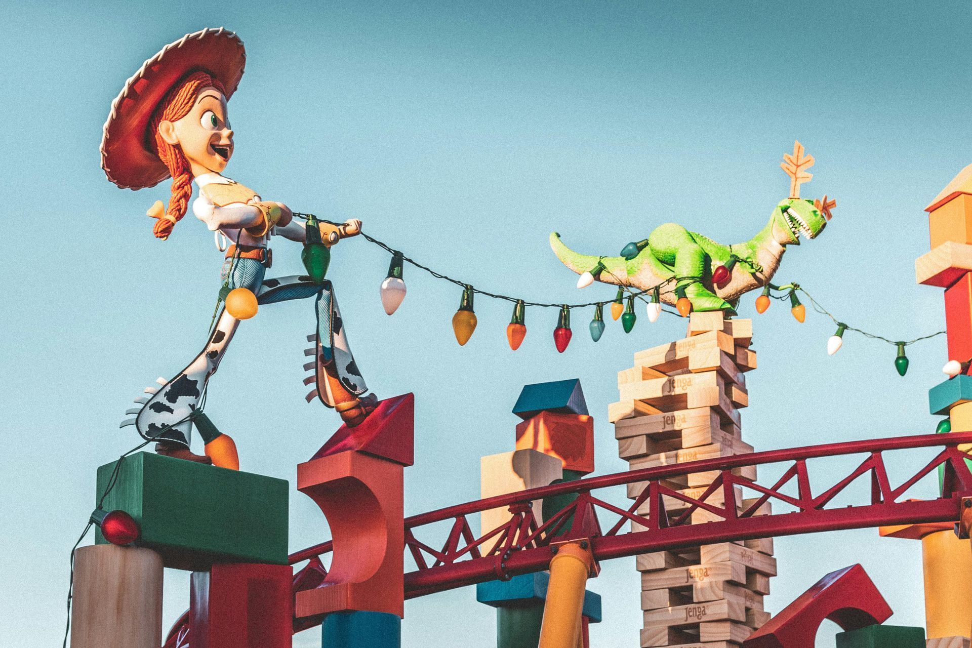 Jessie the cowgirl and Rex the dinosaur, pulling a string of lights, atop toy block structures.