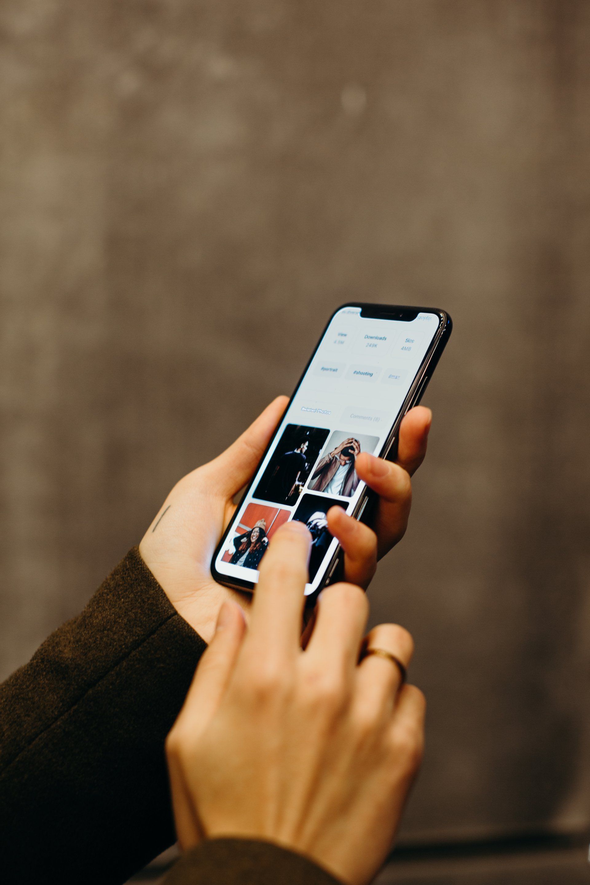 Person holding smartphone, scrolling through a gallery of images on the screen.