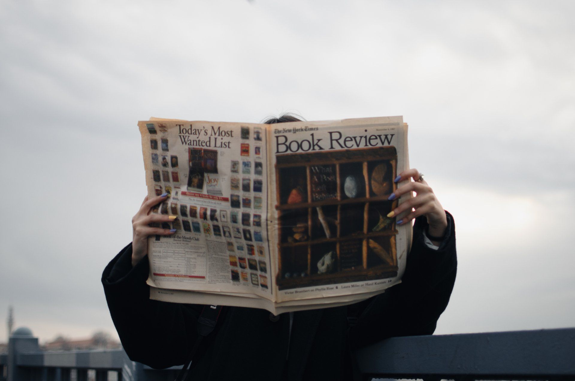 Person holding open newspaper, titled