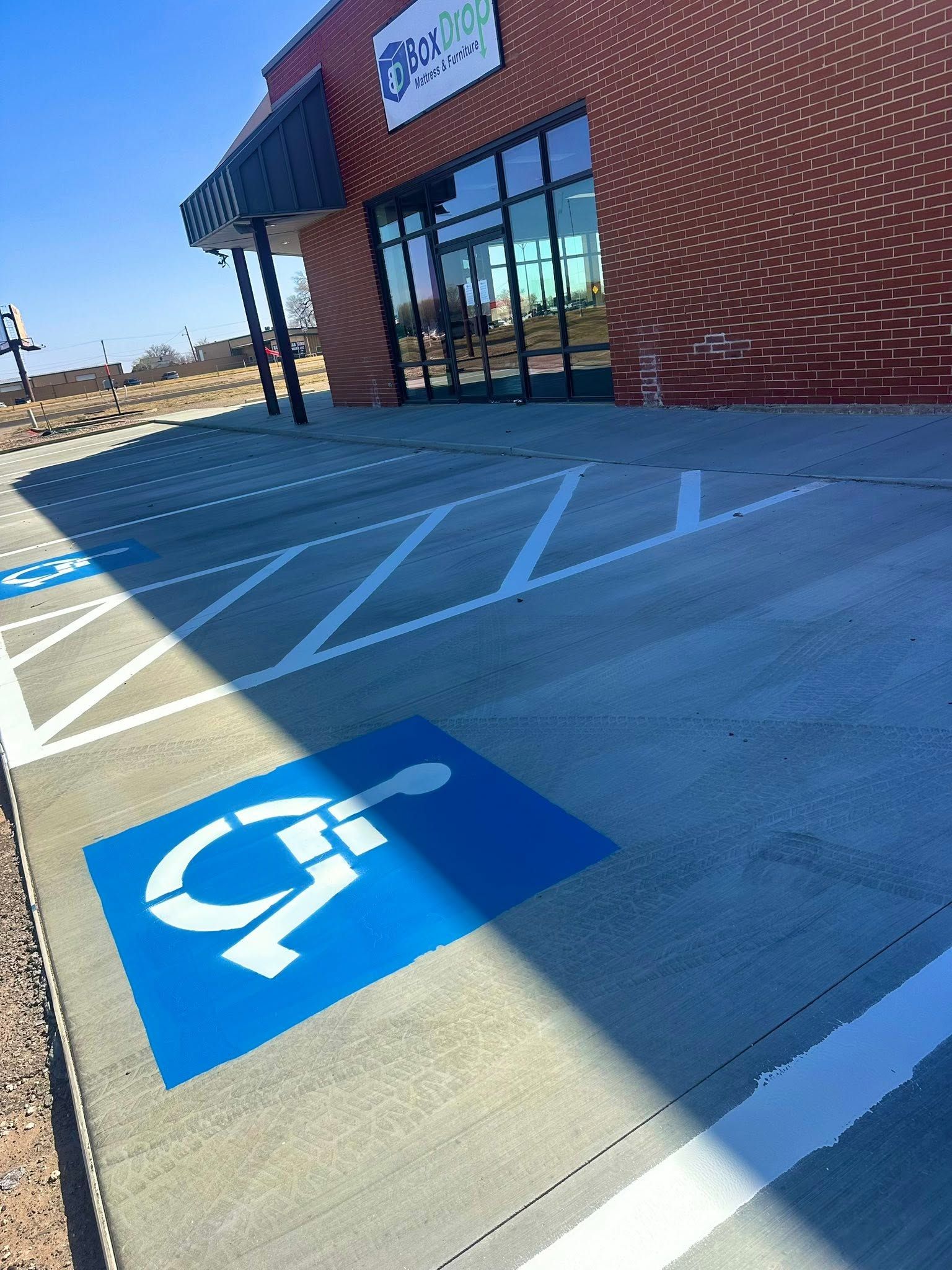 A man is painting a parking lot in front of a sherwin williams paints store