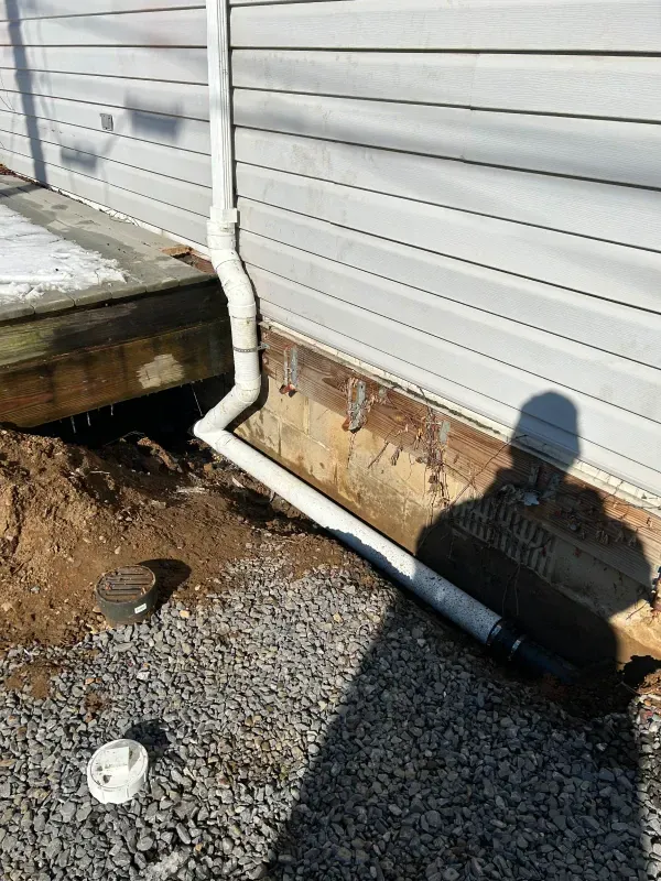 A drain pipe is being installed on the side of a house.