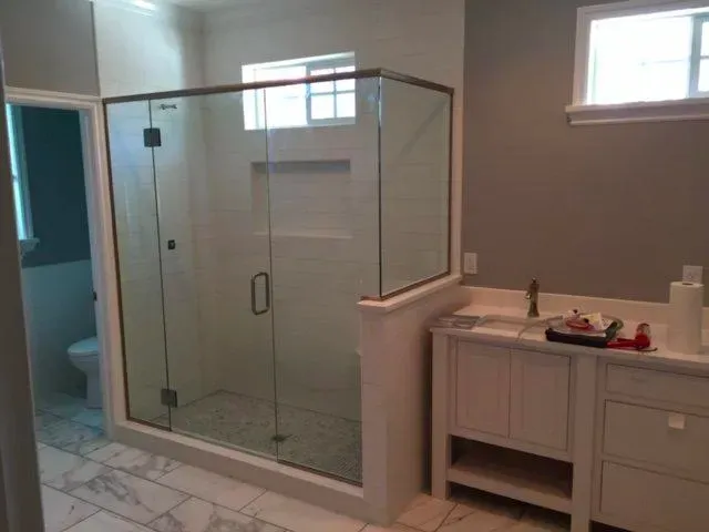 A bathroom with a walk in shower and a sink