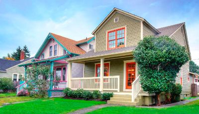 A row of colorful houses are sitting next to each other on a lush green lawn.