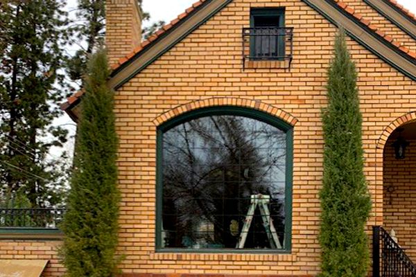 A brick house with arched windows and trees in front of it
