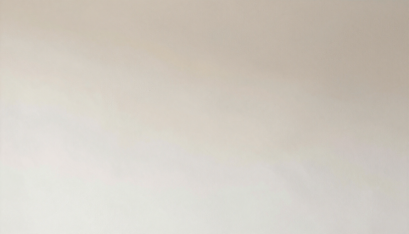 A blurred, smooth surface of light tan or cream color with soft shadows, suggesting a solid object or wall.