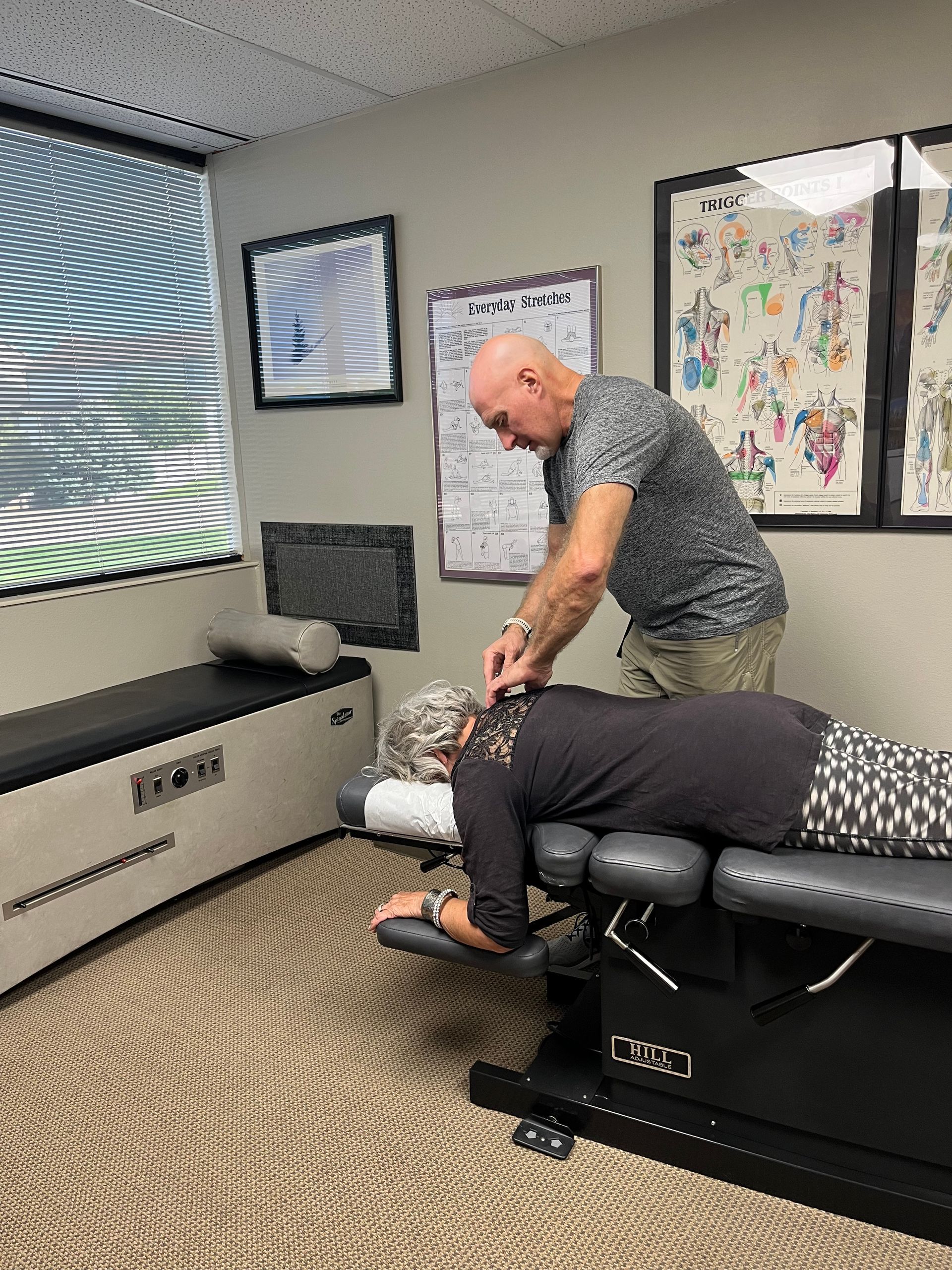 A man wearing a hard hat is kneeling down and looking at a clipboard A little girl is getting a massage from a doctor.