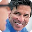A man in a blue shirt and tie is smiling for the camera. A man in a blue shirt and tie is smiling for the camera.