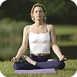 A woman is sitting in a lotus position on a yoga mat in the grass. A woman is sitting in a lotus position on a yoga mat in the grass.