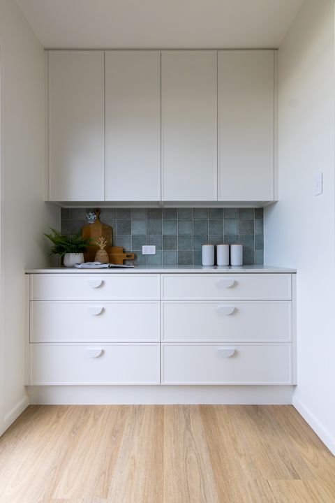 White cabinetry with drawers, gray countertop, and blue tile backsplash.