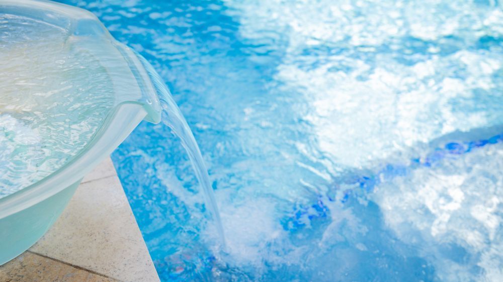 Clear plastic bowl beside a blue bubbling pool or water feature with splashing water.