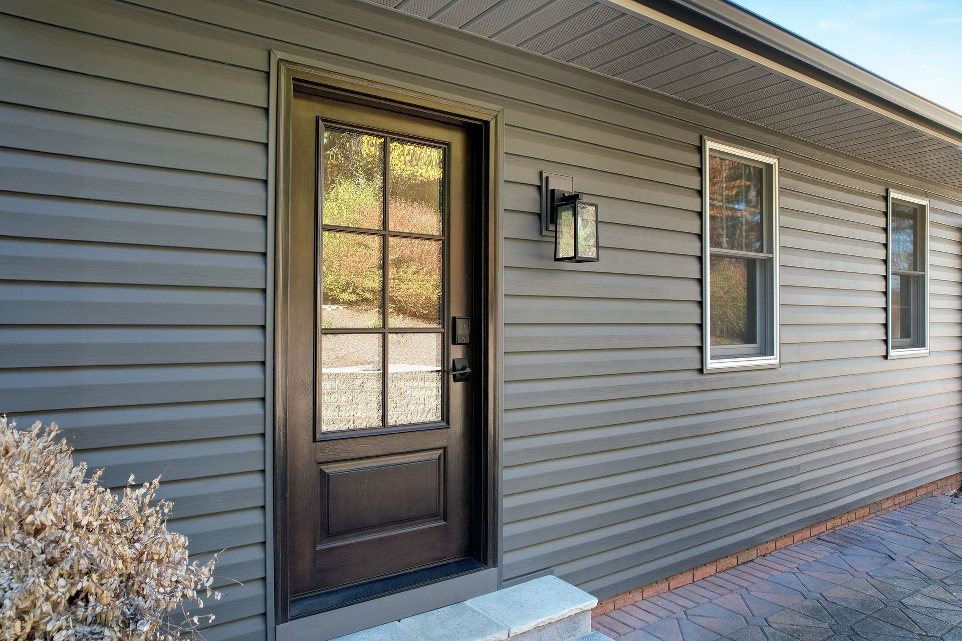 Dark gray siding and door on a house with glass panes; a small window is to the right.