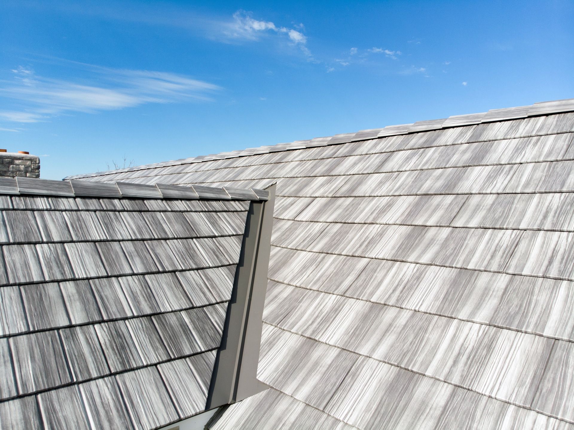 Gray wood shingle roof against a blue sky.