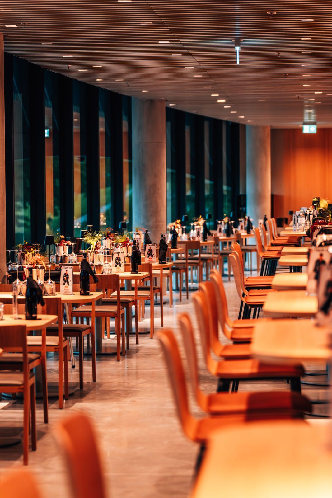 Decken Sie die Tische in einem hellen Restaurant mit türkisfarbenen Stühlen und einer farbenfrohen Wandmalerei im Hintergrund.