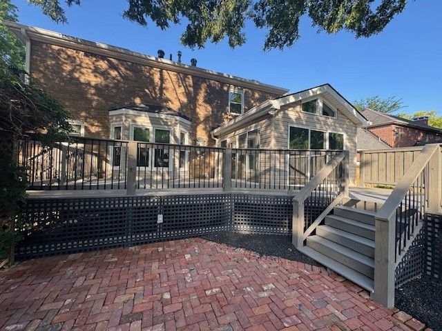 Back of a house with a multi-level deck, brick patio, and steps.